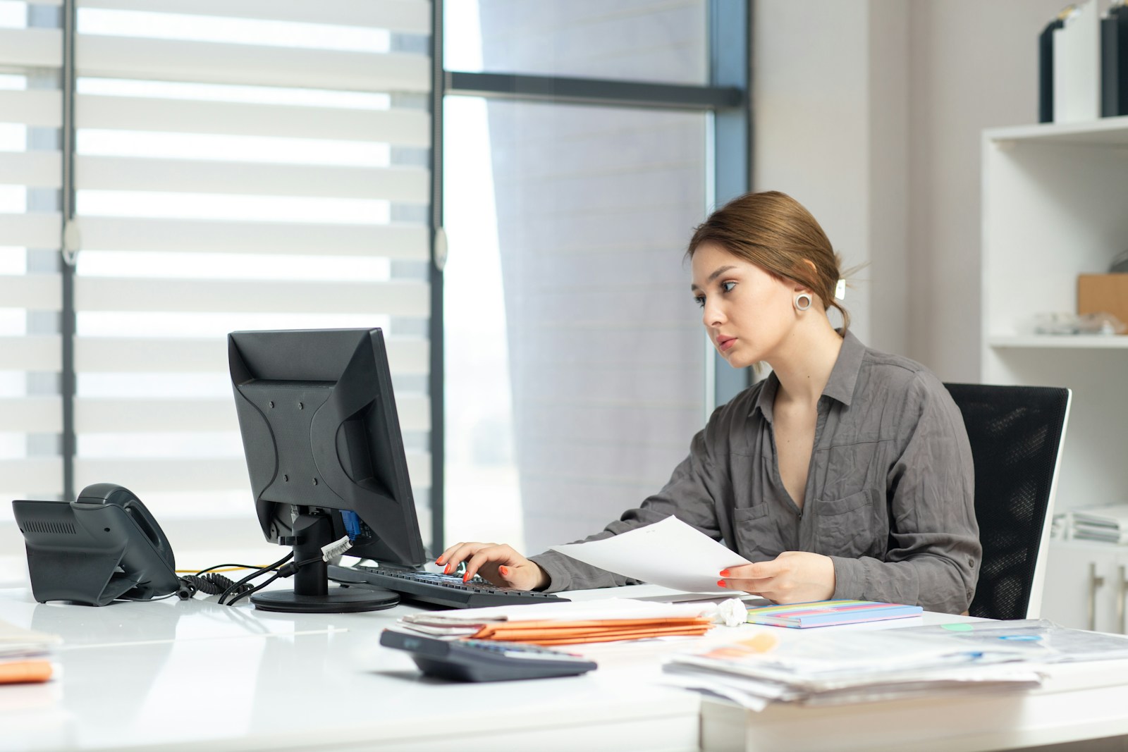 Bookkeeper reviewing records and reports at a bright office desk