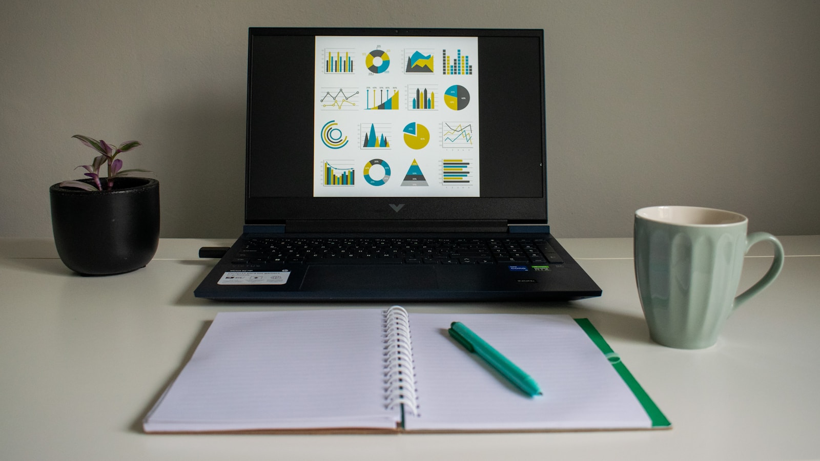 Laptop showing financial charts beside a notebook during a margin review